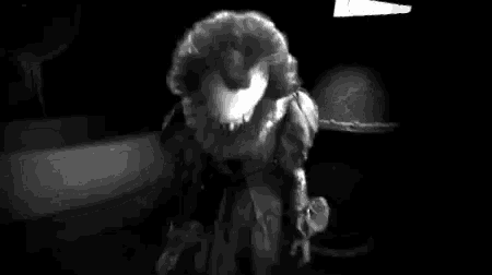 a black and white photo of pennywise from it chapter two holding a white rabbit .
