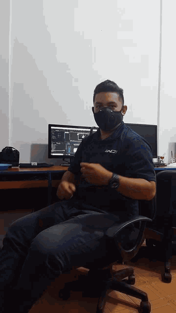 a man wearing a face mask is sitting in front of a computer monitor