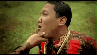 a man with a gold chain around his neck is being touched by another person