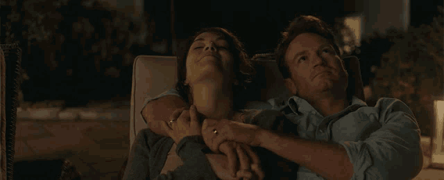 a man and a woman are holding hands while looking up at the sky