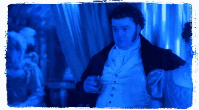 a man in a white vest and black jacket holds a glass in his hand