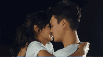 a man and a woman are kissing in a dark room