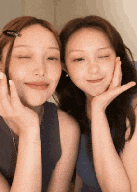 two women are posing for a picture and one has her hand on her face