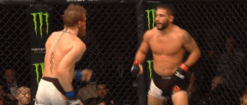 two men are fighting in a cage with monster energy advertisements on the wall
