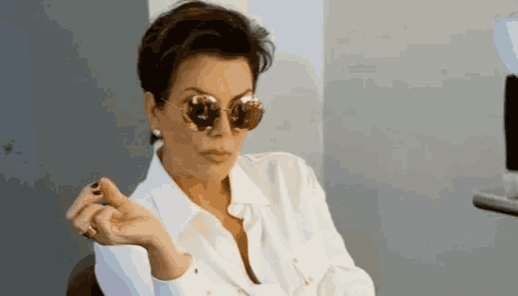 a woman is wearing sunglasses and a white shirt .