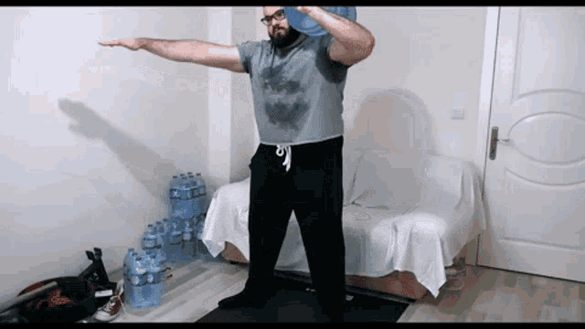 a man is holding a water bottle over his head in front of a couch full of water bottles