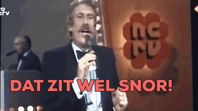 a man singing into a microphone with the words dat zit wel snor in red