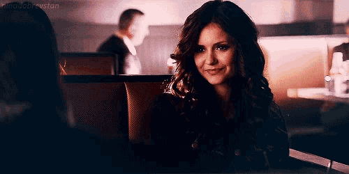 a woman is sitting at a table in a restaurant and smiling