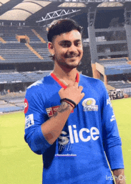 a young man wearing a blue slice jersey stands on a field