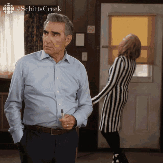 a scene from schitt 's creek shows a man and woman standing in front of a door