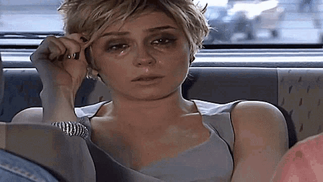 a woman with a tear running down her face is talking on a cell phone