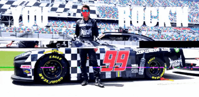 a man wearing a mask stands next to a race car with the number 99 on it