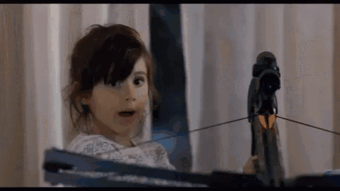 a little girl looking at a crossbow with a surprised expression on her face