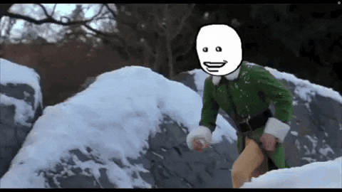 a man in a green elf costume is running through the snow with a white face on his head .