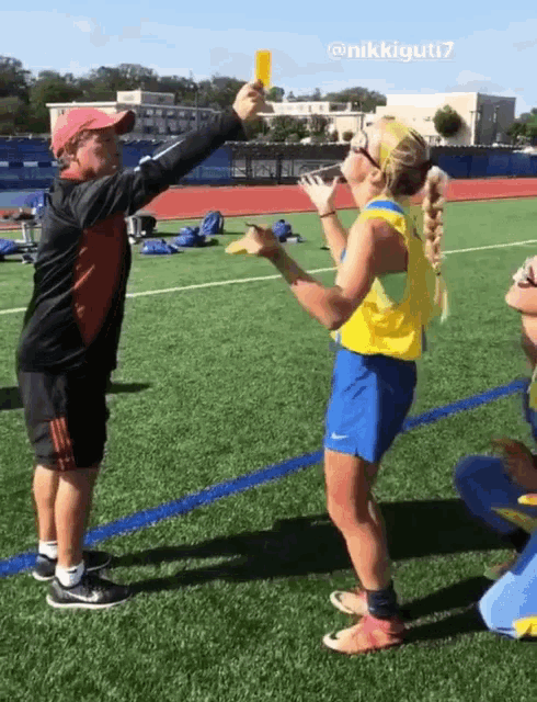 a man is giving a yellow card to a girl on the field
