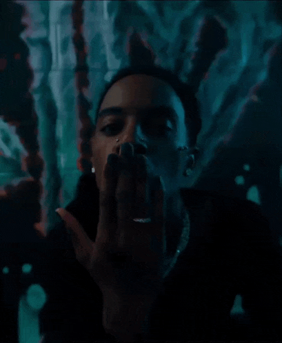a man with a ring on his finger is smoking a cigarette in a dark room