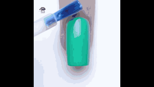 a person is painting their nails with green nail polish .