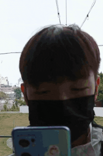 a man wearing a face mask is looking at his phone