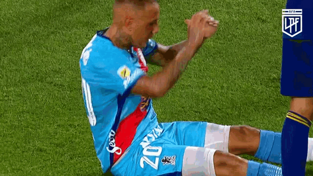 a soccer player in a blue jersey is kneeling on the grass .