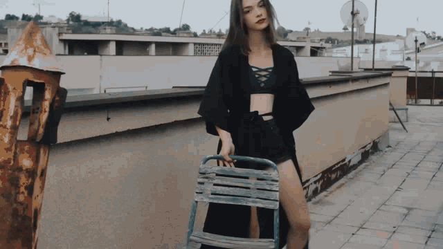 a woman in a black kimono holds a chair