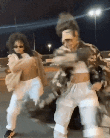 a man and a woman are dancing together in a parking lot at night .