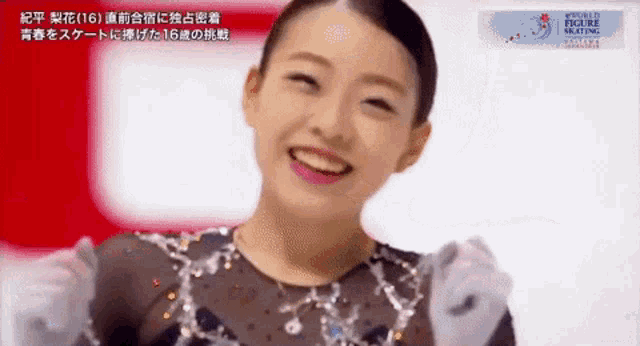 a female figure skater is smiling and holding her hands up in the air .