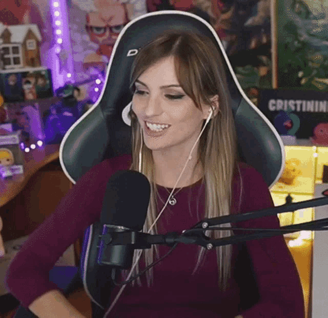 a woman wearing headphones and a purple shirt is sitting in front of a microphone and a sign that says cristinini
