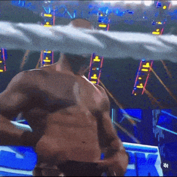 a man without a shirt is standing in a boxing ring .