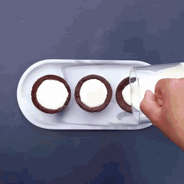 a glass of milk is being poured into a plate of cookies