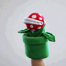 a person is holding a puppet of a carnivorous plant