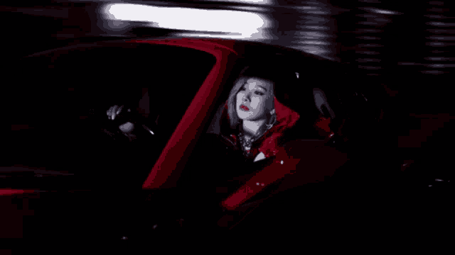 a woman in a red jacket is driving a car