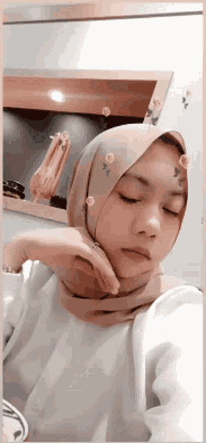 a woman wearing a hijab is taking a picture of herself in front of a mirror .