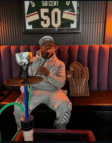 a man smoking a hookah in front of a framed 50 cent jersey