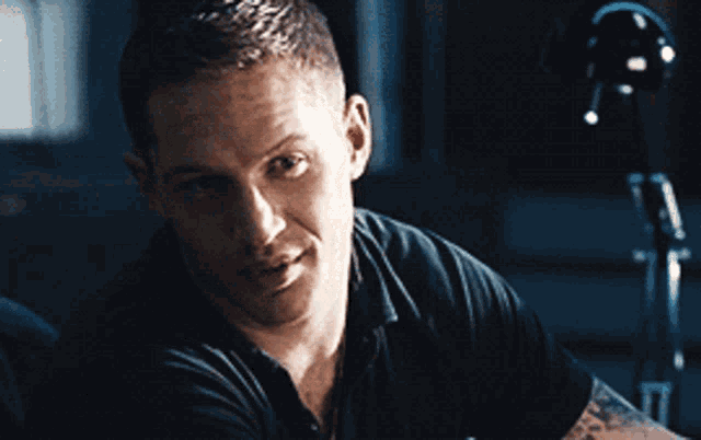 a man in a black shirt with a tattoo on his arm is smiling