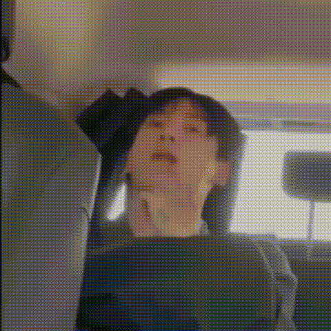 a person is sitting in the back seat of a car with their head down .