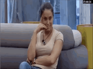 a woman is sitting on a couch with her arms crossed and her hand on her forehead .