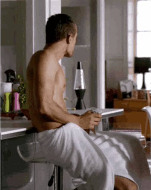 a shirtless man wrapped in a white towel sits on a stool