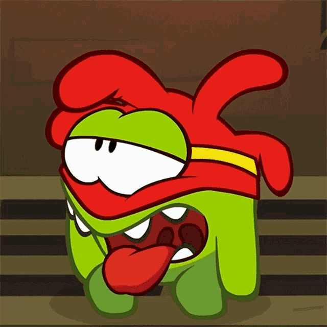 a green cartoon character with a red headband sticking out its tongue