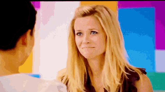 a woman with blonde hair and blue eyes is looking at a man