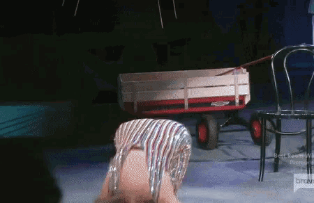 a red and white wagon is pulled by a woman in a silver outfit