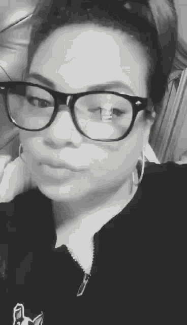 a black and white photo of a woman wearing glasses .