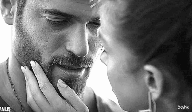 a woman is touching the face of a man with her hand .