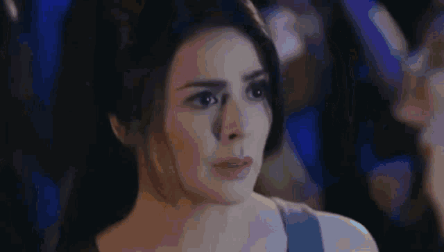 a woman is looking at the camera in a dark room .
