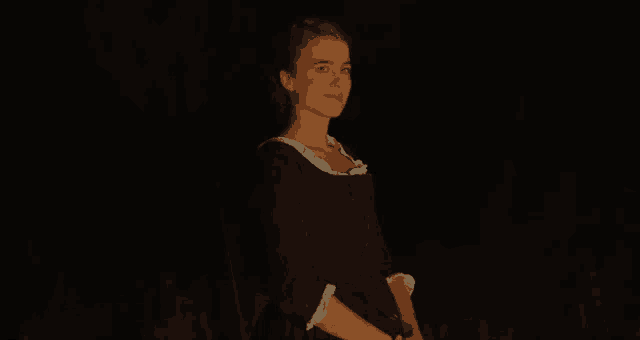 a woman in a black dress with white ruffles is standing in the dark