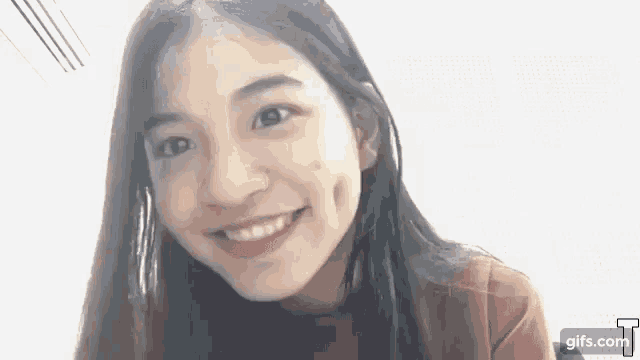 a close up of a young girl smiling and looking at the camera .