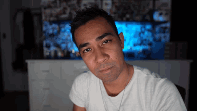 a man in a white shirt looks at the camera with a blue background