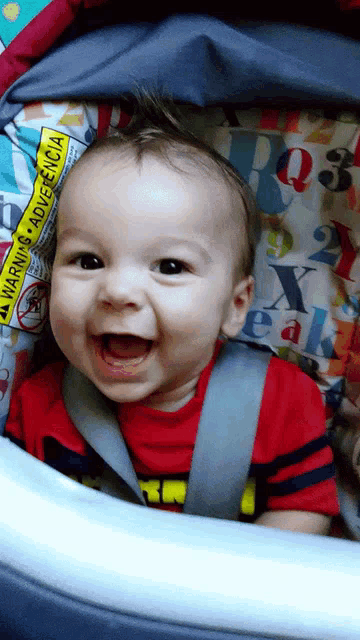 a baby is smiling in a high chair with a warning advertencia on the back