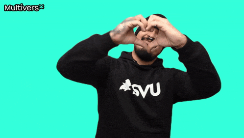 a man making a heart shape with his hands in front of a green background that says multivers on it
