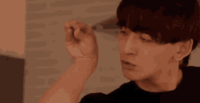a young man in a black shirt is holding something in his hand in a kitchen .