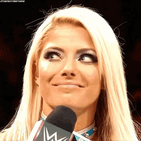 a woman with blonde hair is talking into a microphone and making a funny face .
